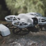 A small white drone with a controller sitting on a rock